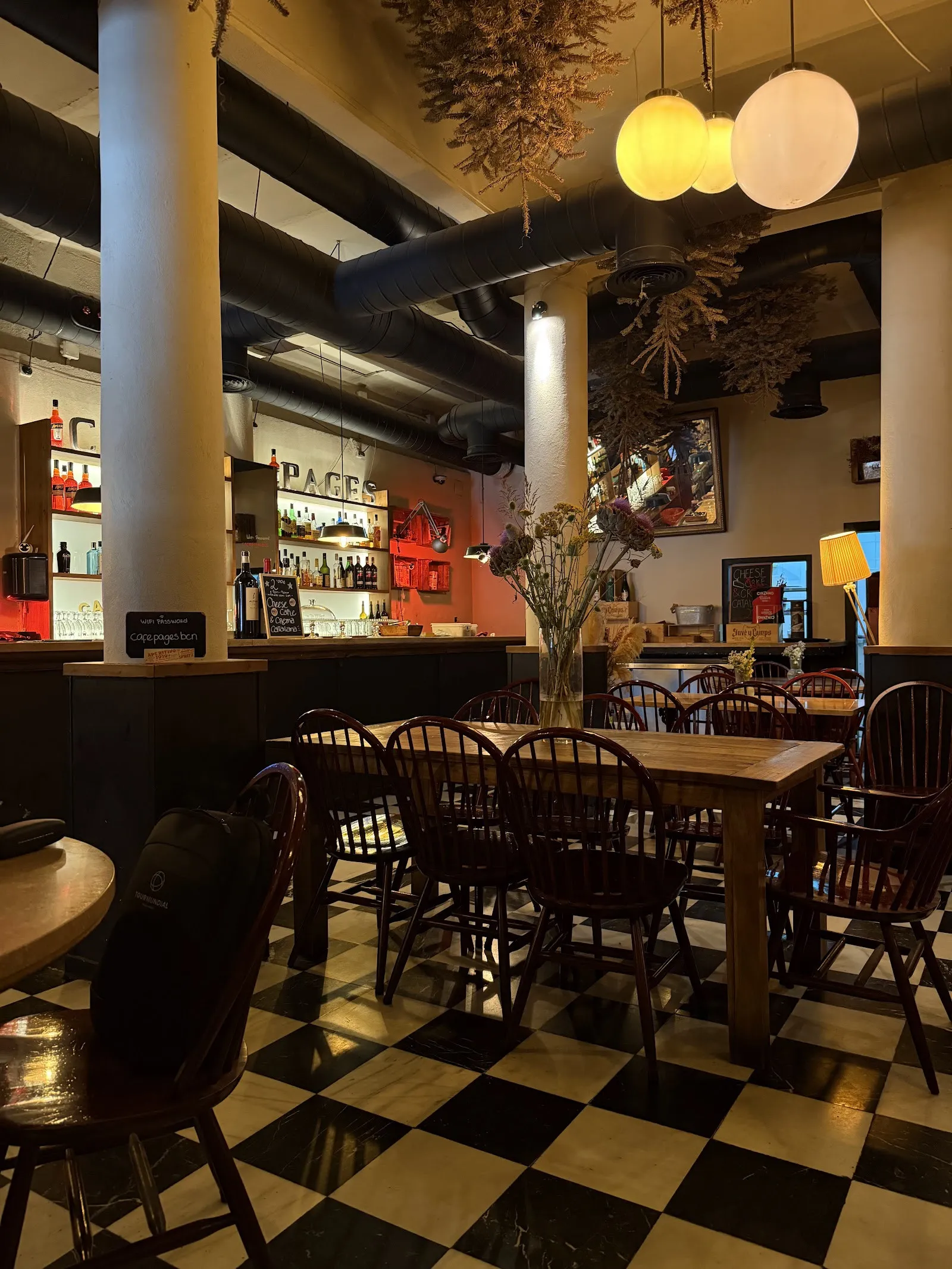 El comedor, con suelo de damero, mesas de madera y lámparas