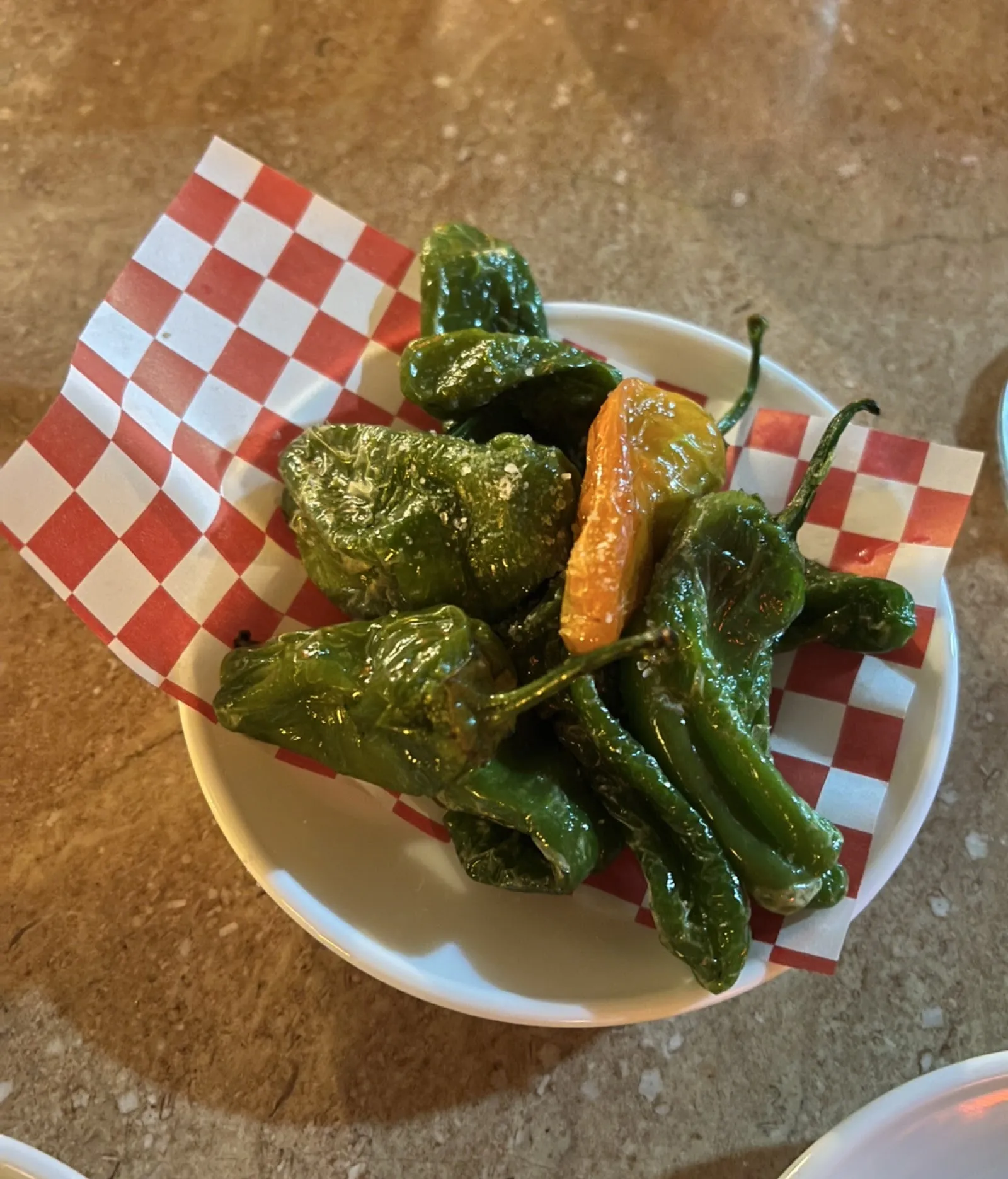 Pimientos verdes fritos sobre papel de cuadros rojos y blancos